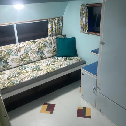 Restored caravan lounge with palm print upholstery and a teal cushion